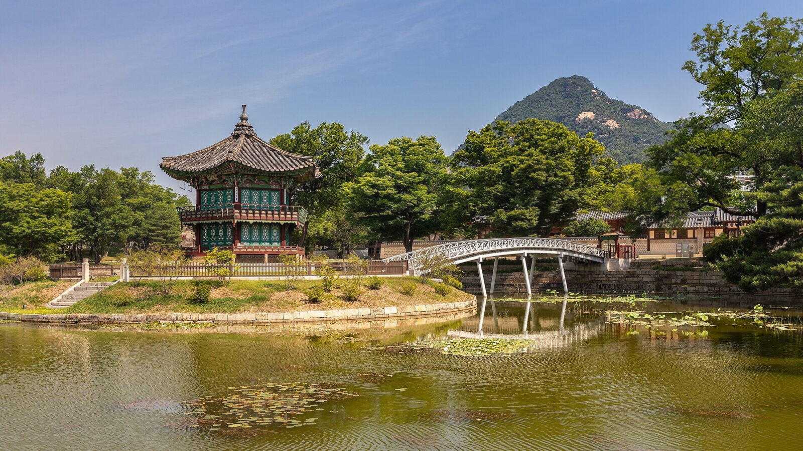 Hyangwonjeong Pavilion in a pond and Chwihyanggyo Bridge with blue sky at Gyeongbokgung Palace in Seoul, South Korea