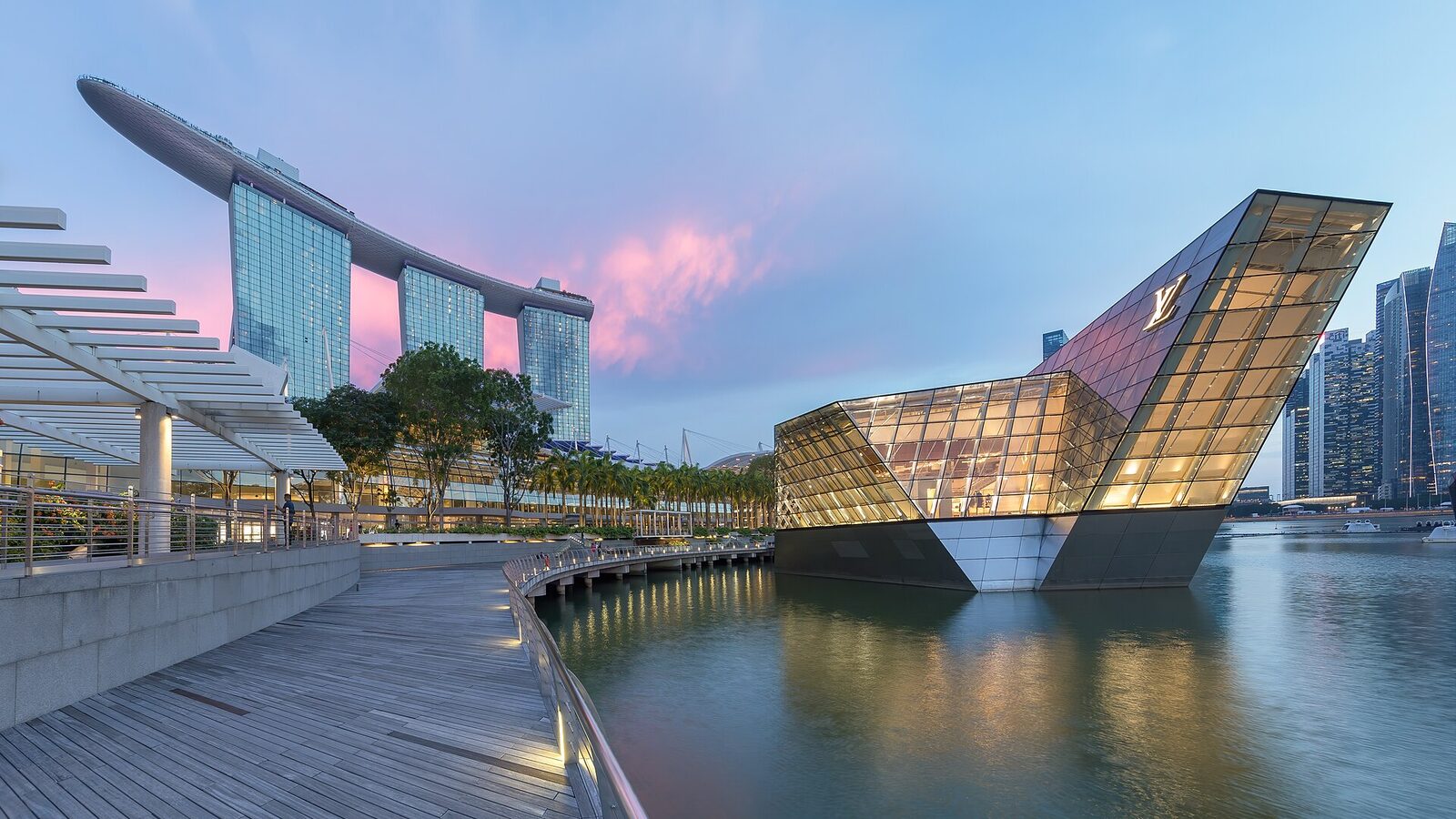 Marina Bay Sands and illuminated polyhedral building Louis Vuitton over the water at blue hour with pink clouds in Singapore