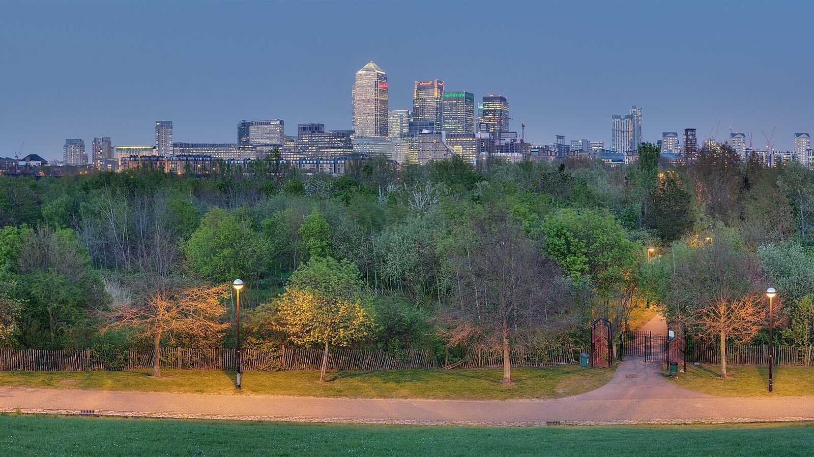 A panoramic view of the Stave Hill Ecological Park in Rotherhithe, London. In the background is Canary Wharf and Isle of Dogs
