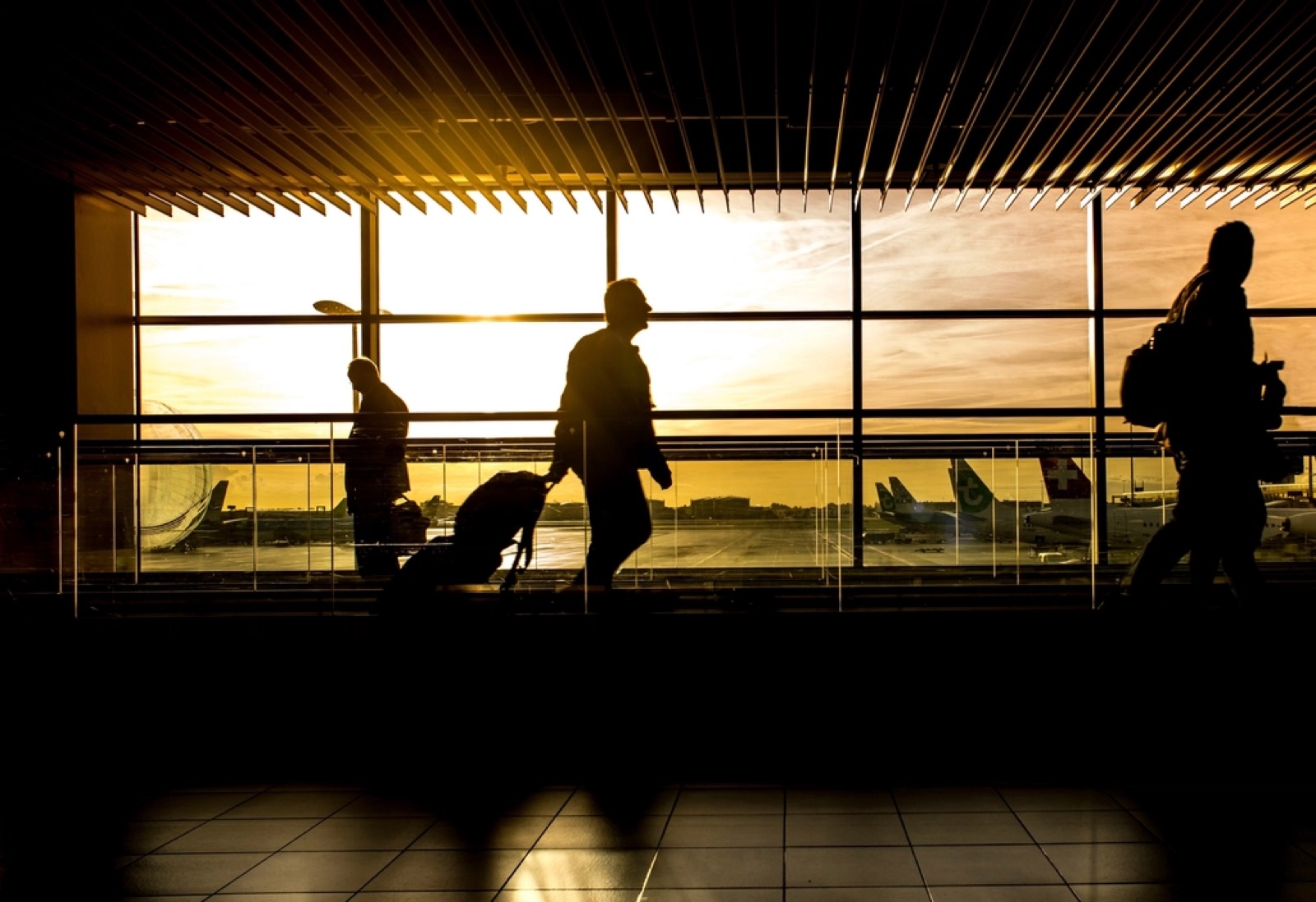Travellers at an airport gate at sunset
