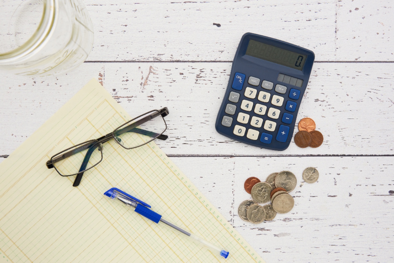 Calculator, glasses and coins on a desk — budgeting